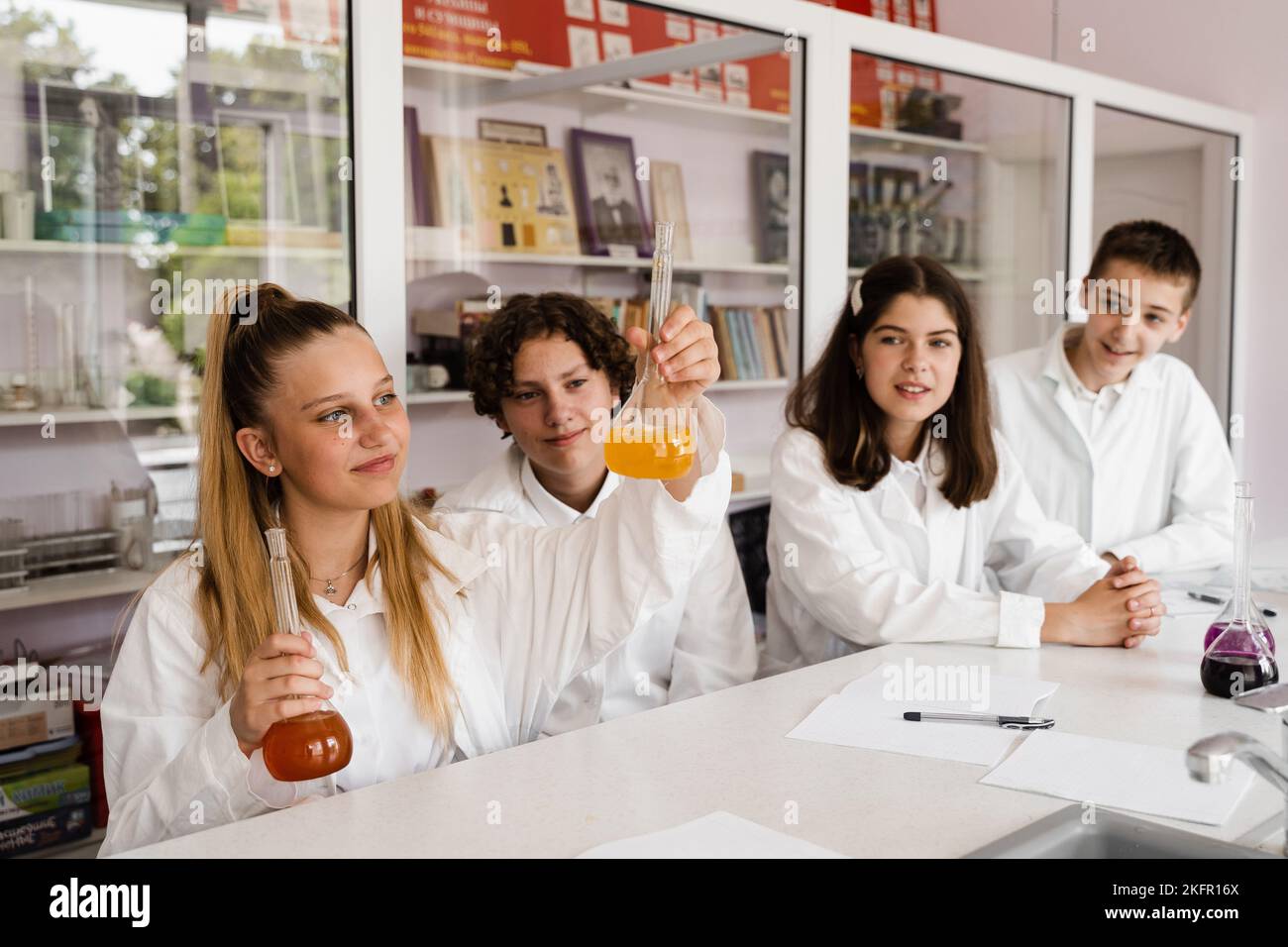 Chemistry lesson. Schoolgirl and classmates holds flask for experiments ...