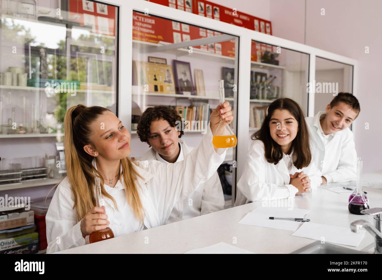 Chemistry lesson. Schoolgirl and classmates holds flask for experiments ...