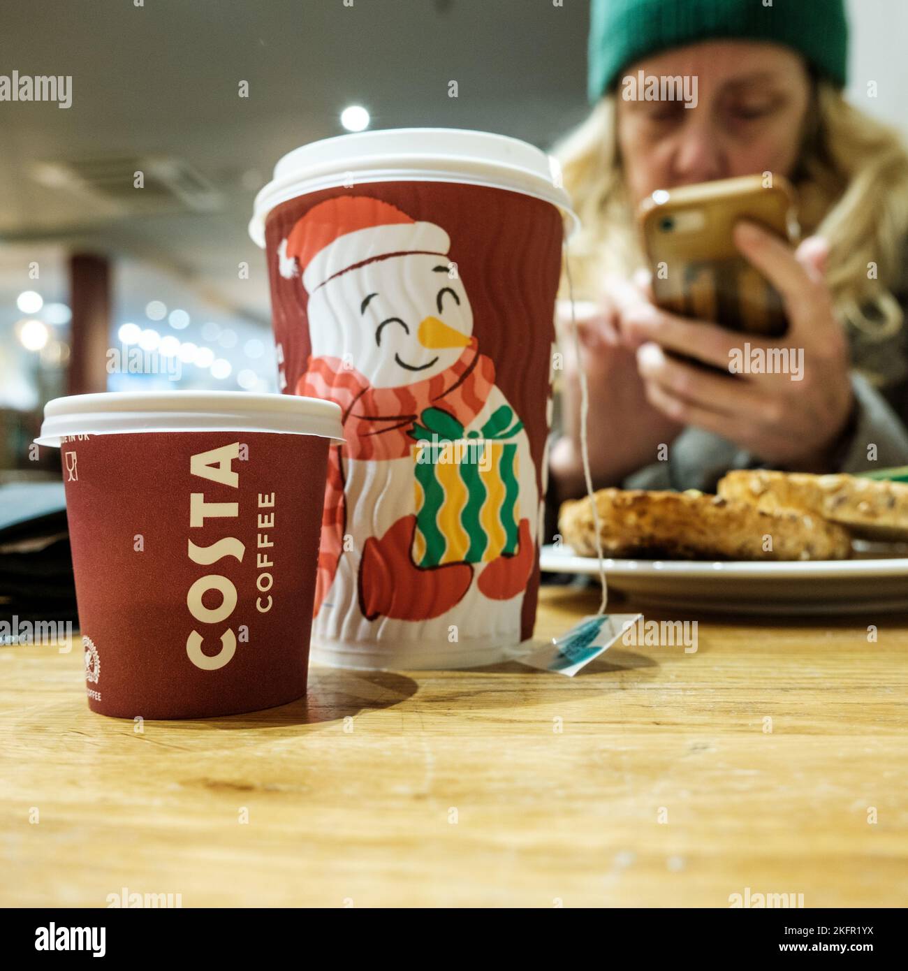Epsom, Surrey, London UK, November 19 2022, Woman Sitting Alone in A Costa Coffee Shop Using A Mobile Or Smartphone Stock Photo