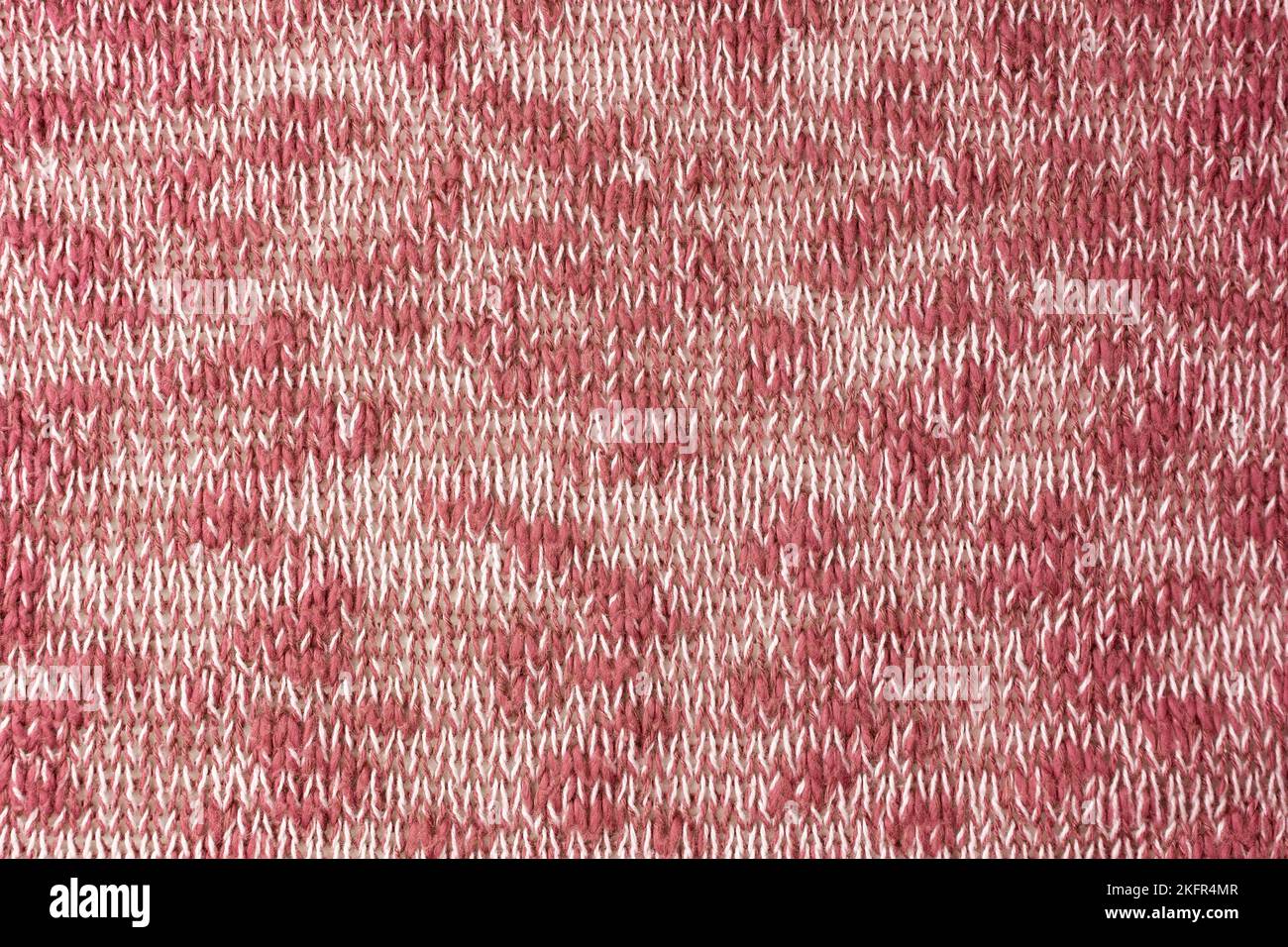 Close up background of knitted wool fabric made of viscose yarn. Mix of red and white color, melange wool knitwear texture. Abstract knitted jersey ba Stock Photo