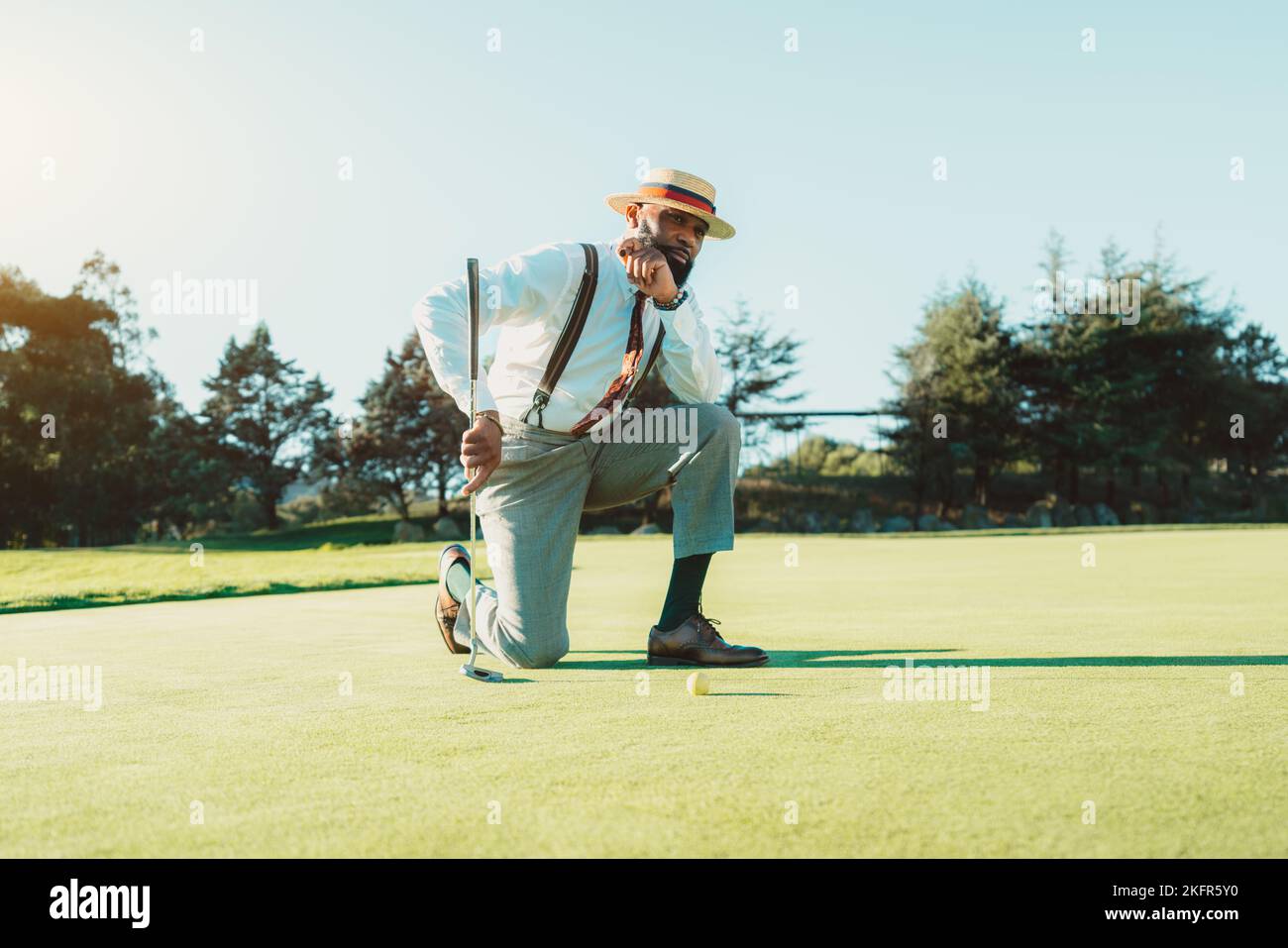 A handsome dapper black man in an elegant outfit with a straw hat and
