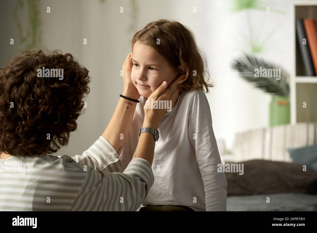 Loving mother stroking her little son and telling the words of support to him while they sitting in the room Stock Photo