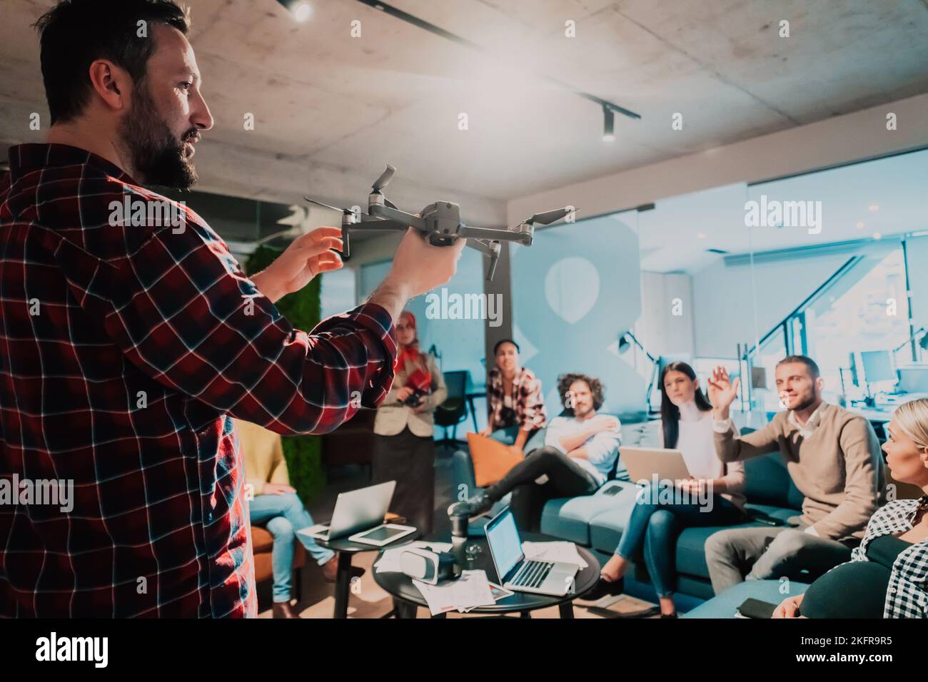 A bearded man in a modern office explaining to his young diverse team how a drone working  Stock Photo