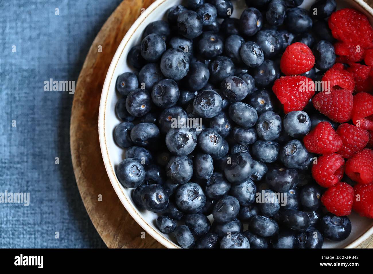 Fresh selected raspberries and blueberries in a bowl. Healthy snack. Berries for dessert. Close-up. Stock Photo