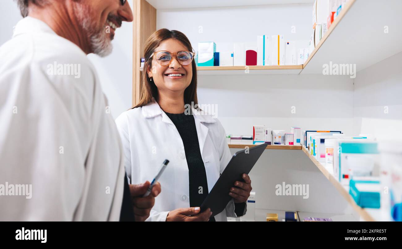 Two pharmacists doing a stock take using a tablet in a drug store
