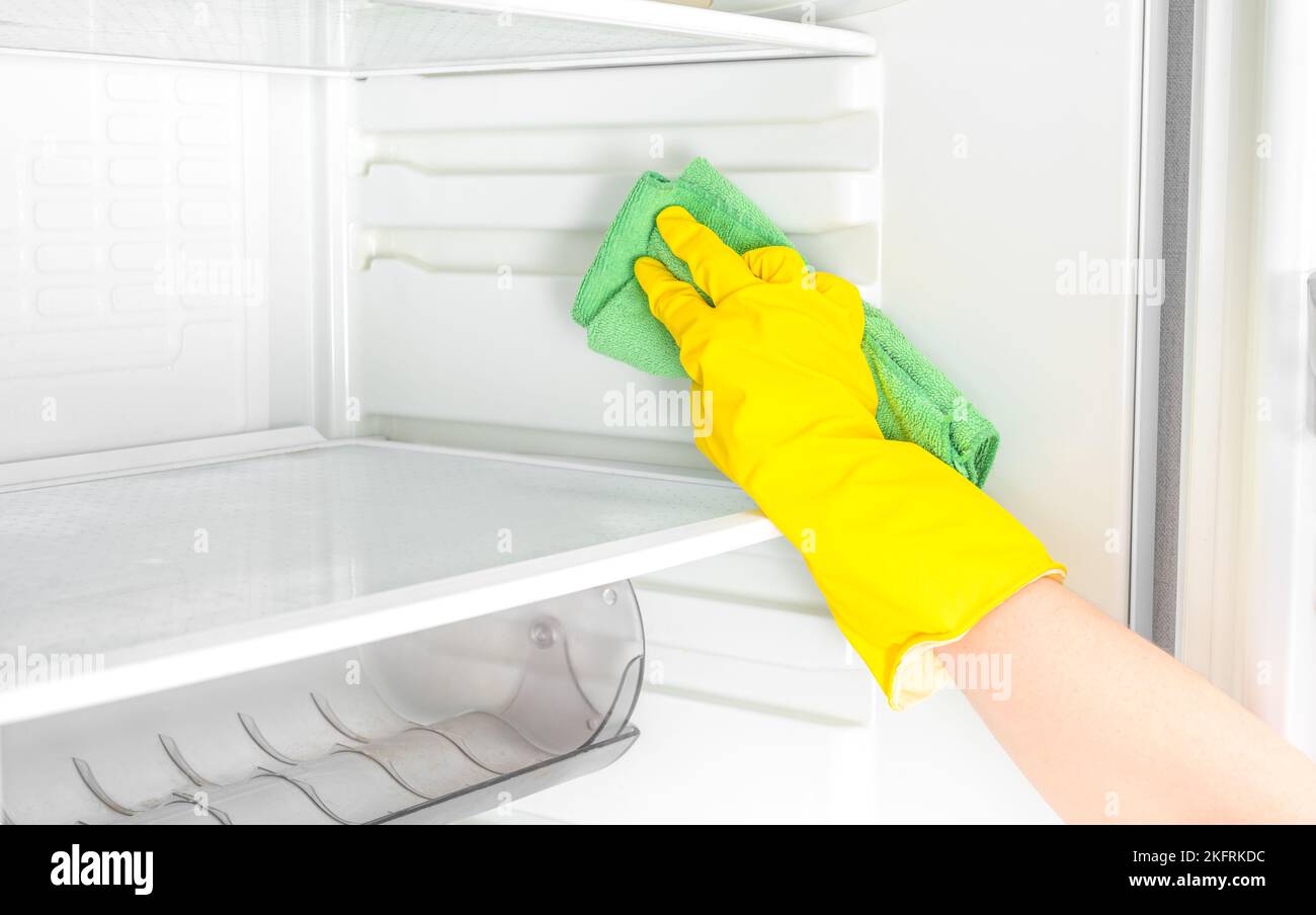 Hand cleaning refrigerator. Person washing refrigerator with rag