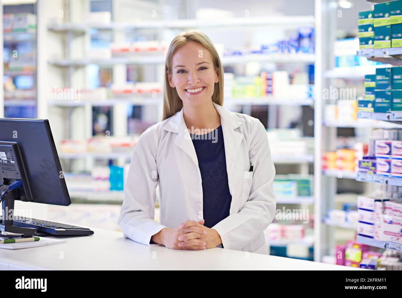 How can I help. Portrait of an attractive pharmacist standing at the prescription counter. Stock Photo