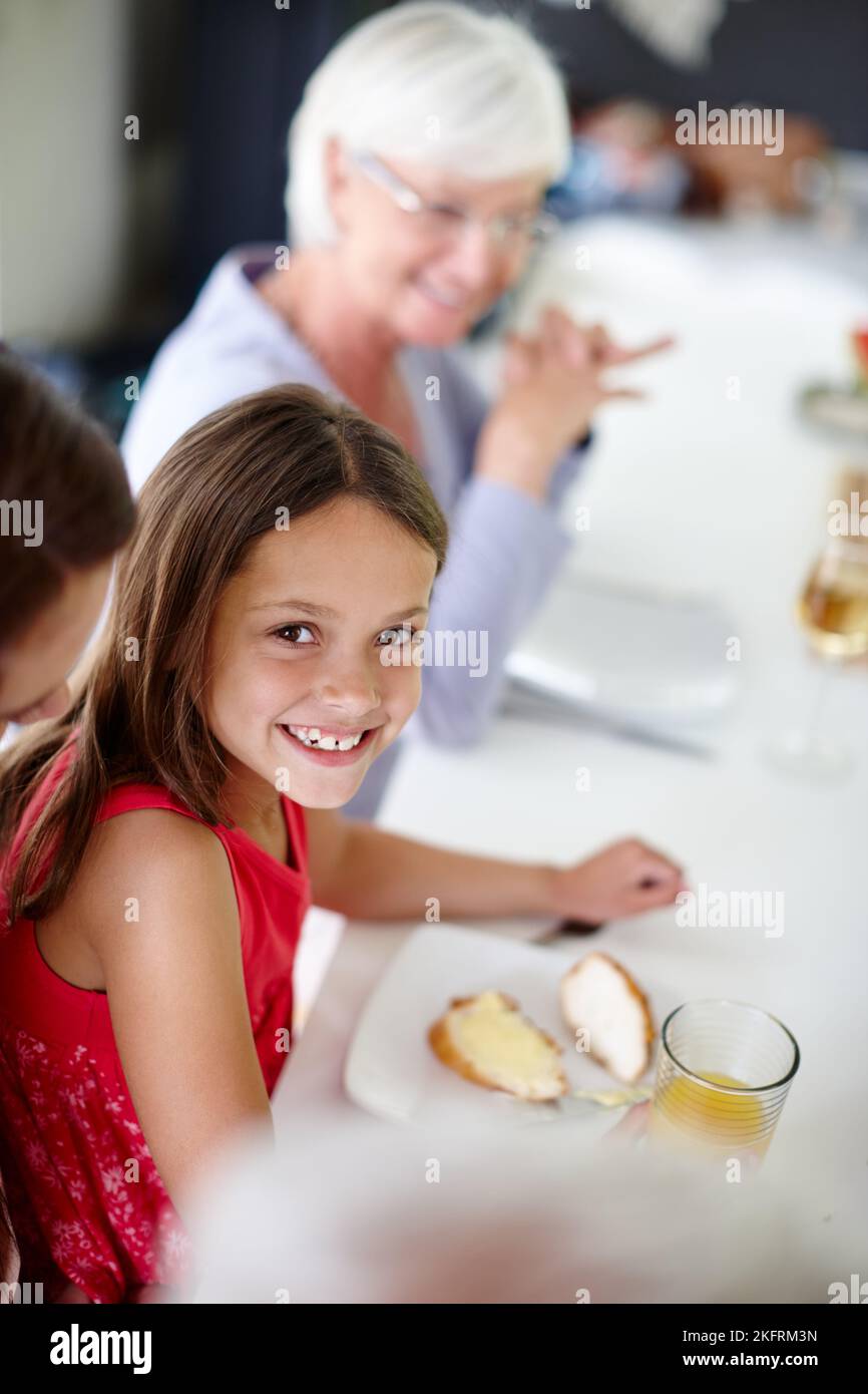 Enjoying yummy food with her family. a little girl having lunch with ...