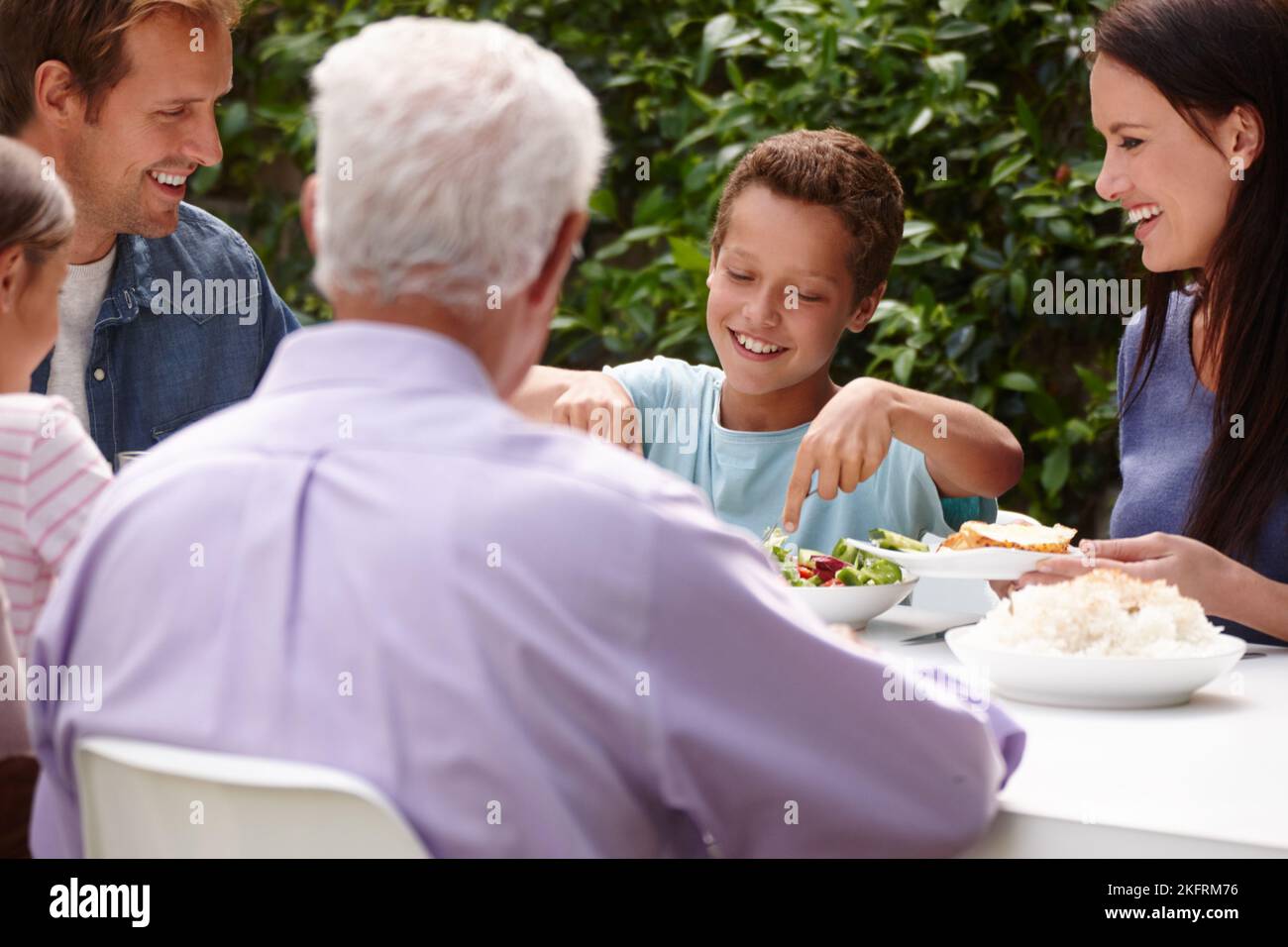 Lets eat. a happy multi-generational family having a meal together outside. Stock Photo
