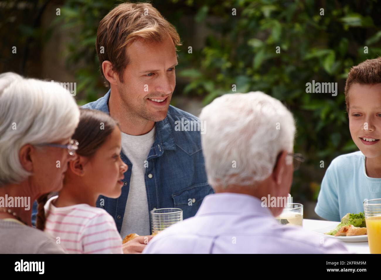 Sharing a meal as a family. a happy multi-generational family having a meal together outside. Stock Photo