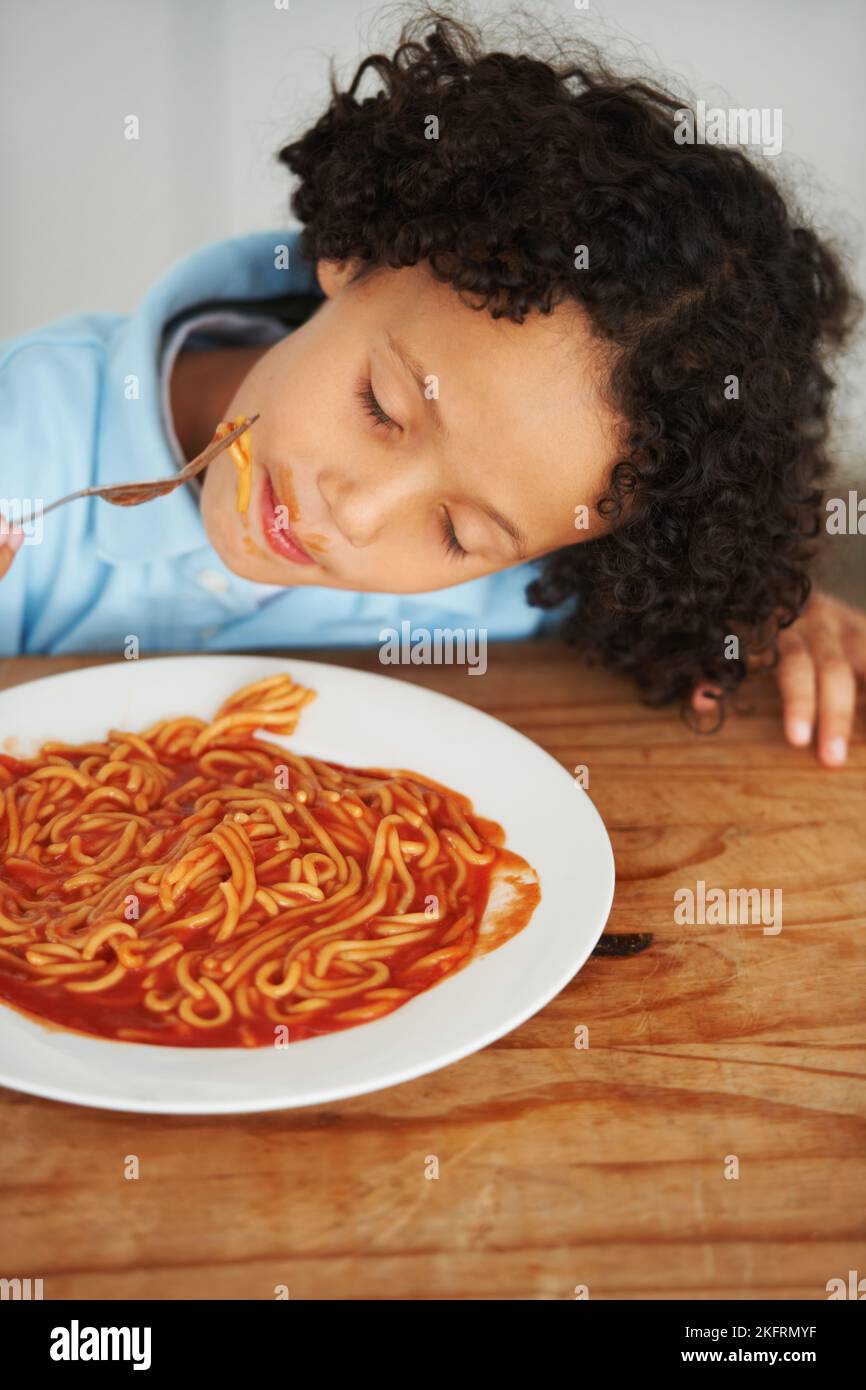 Spaghetti is my favourite. A cute young boy eating spaghetti with his eyes closed. Stock Photo