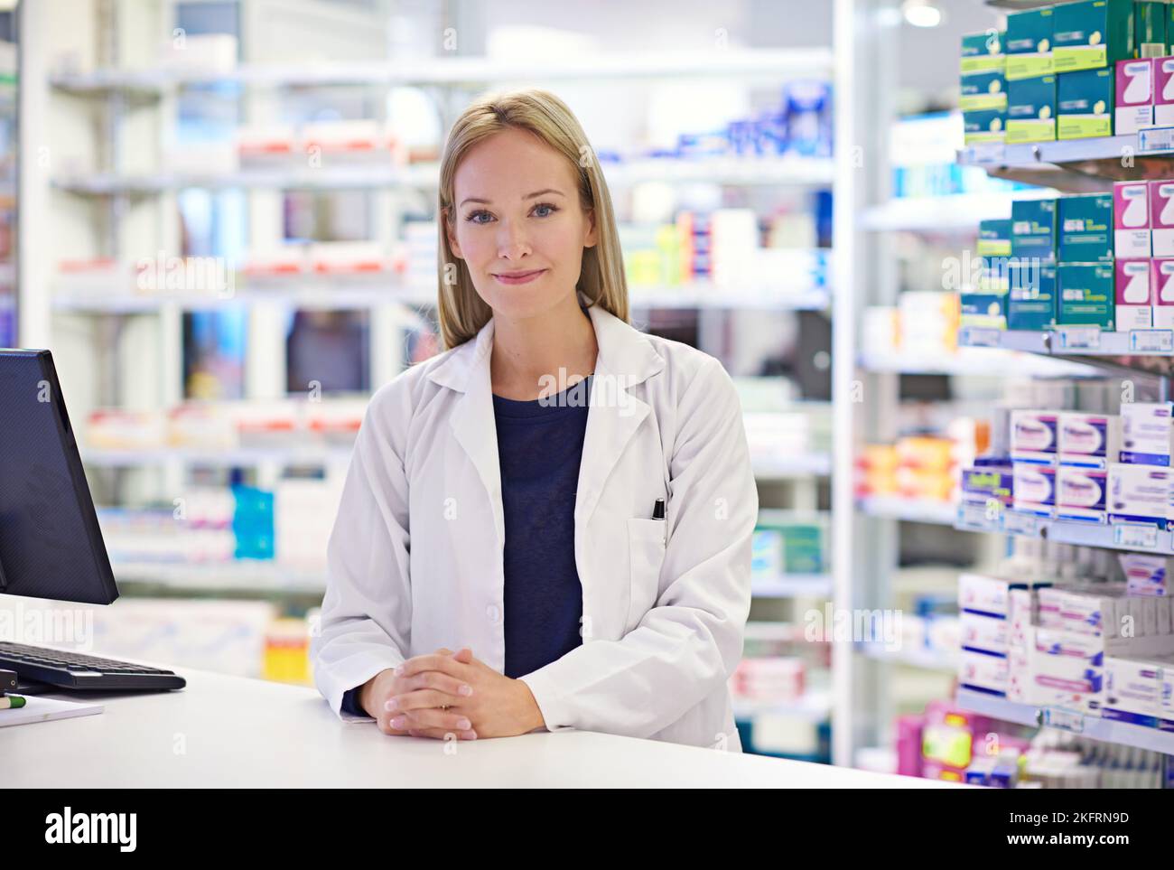 What seems to be the trouble. Portrait of an attractive pharmacist standing at the prescription counter. Stock Photo