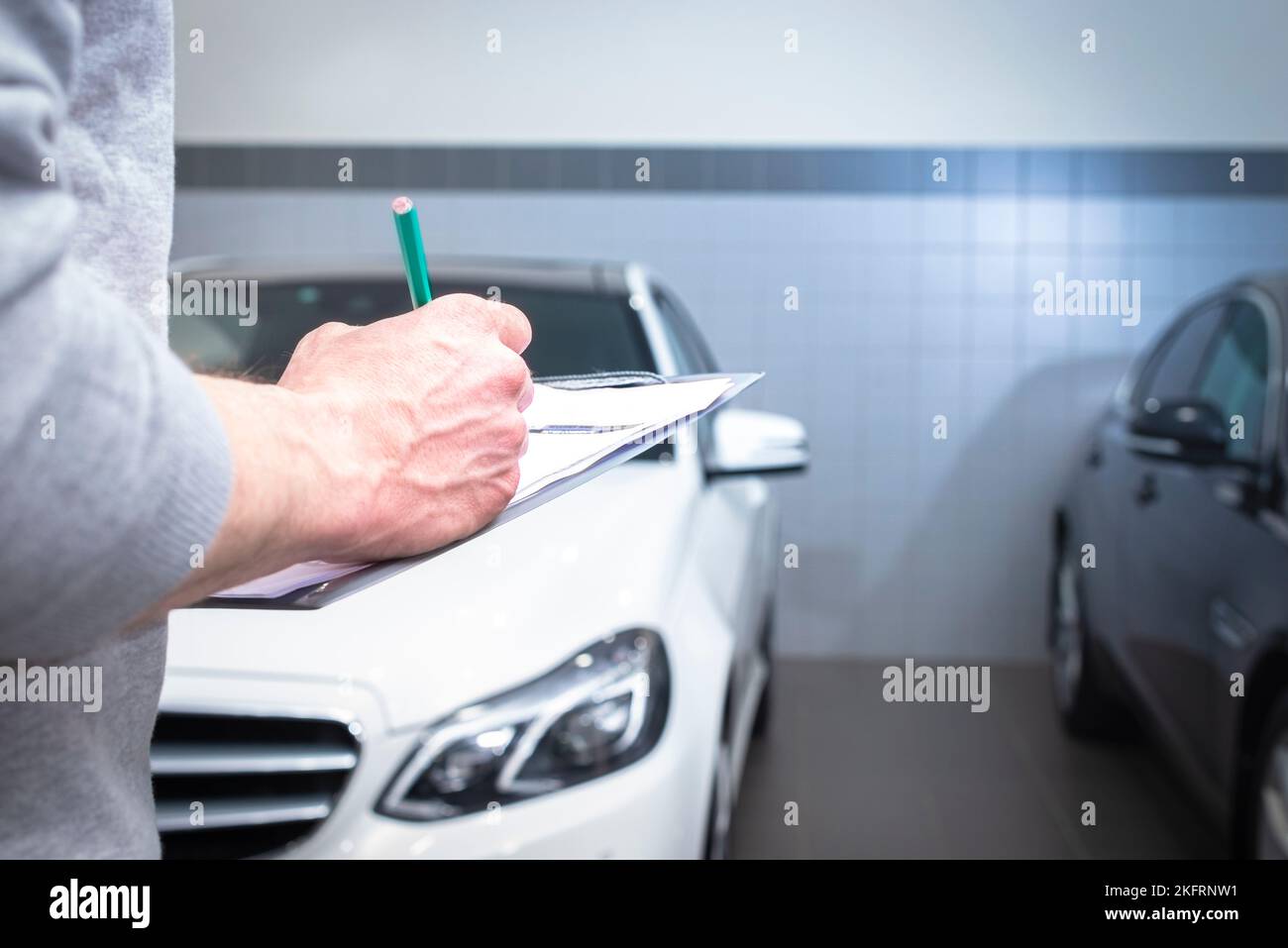 car service, repair, maintenance concept -  mechanic writing to the clipboard at workshop warehouse, technician doing the checklist for repair machine Stock Photo