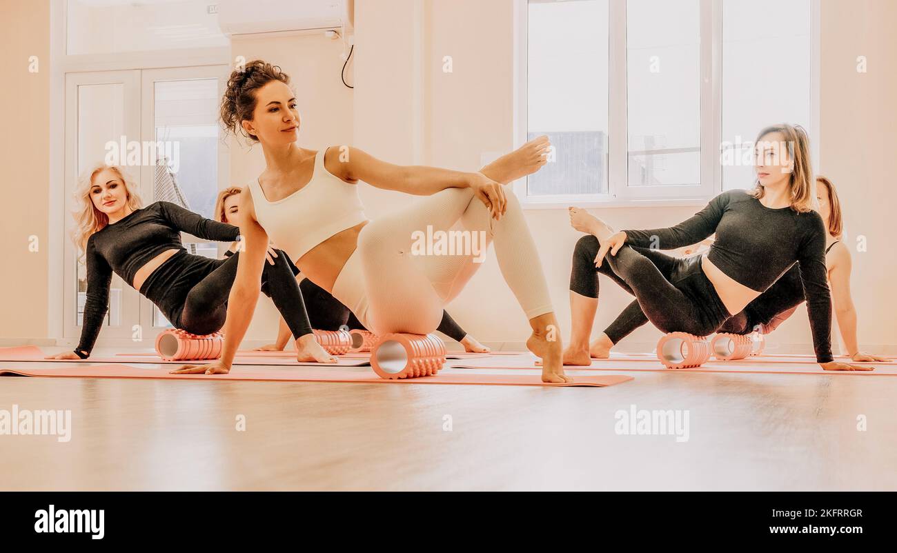Middle aged well looking women, performing fascia exercises on the floor using a massage foam roller - tool to relieve tension in the back and relieve Stock Photo