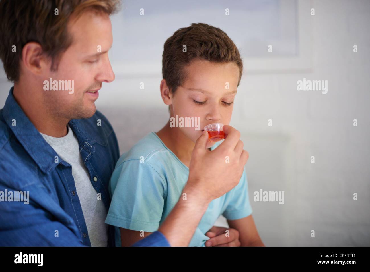 Youll feel better once youve had this. a caring father giving his sick little boy some medicine at home. Stock Photo