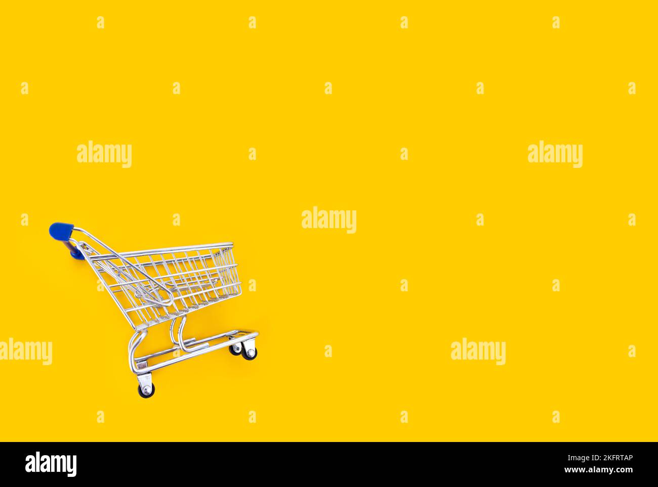 empty shopping cart over yellow background, mini metal cart isolated on color background Stock Photo