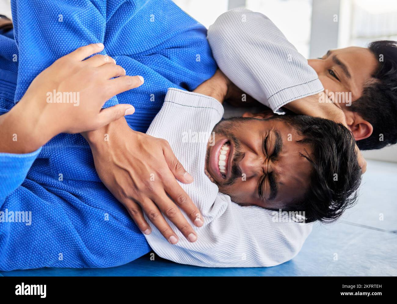 Karate, martial arts and men in choke hold on gym mat for wrestling game, match and practice. Fitness, sport and male athletes doing taekwondo for Stock Photo