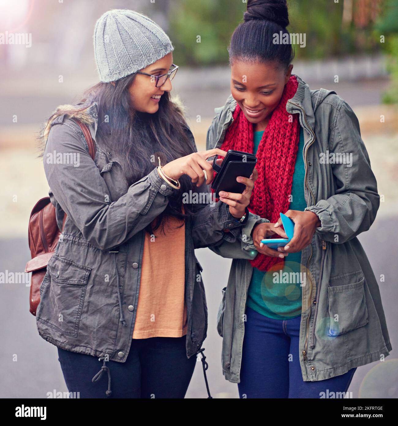 Read this...two girlfriends looking at a cellphone while on campus. Stock Photo