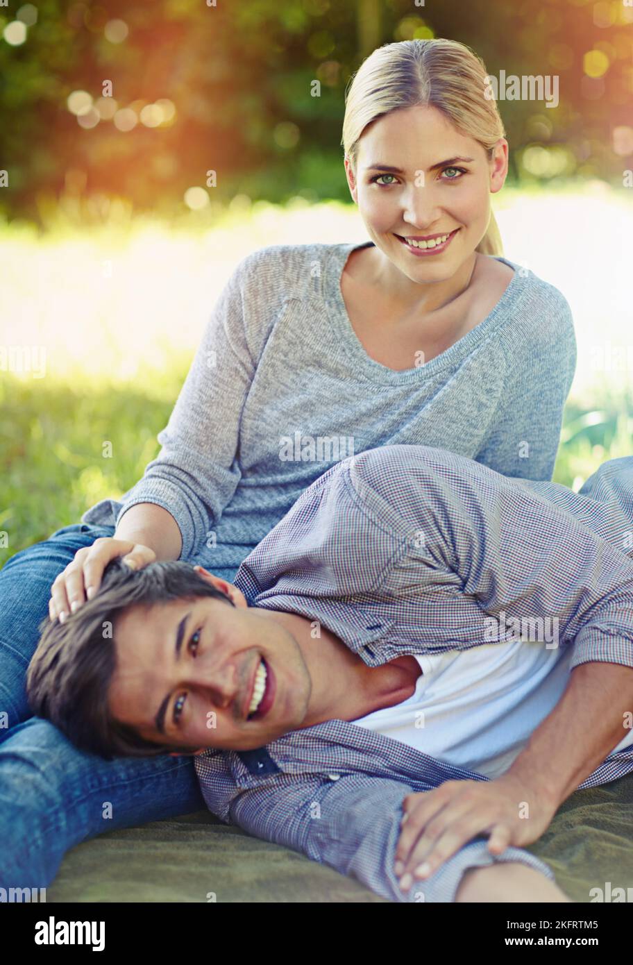 Love at leisure. a happy young couple lying on the grass and sharing an affectionate moment together. Stock Photo