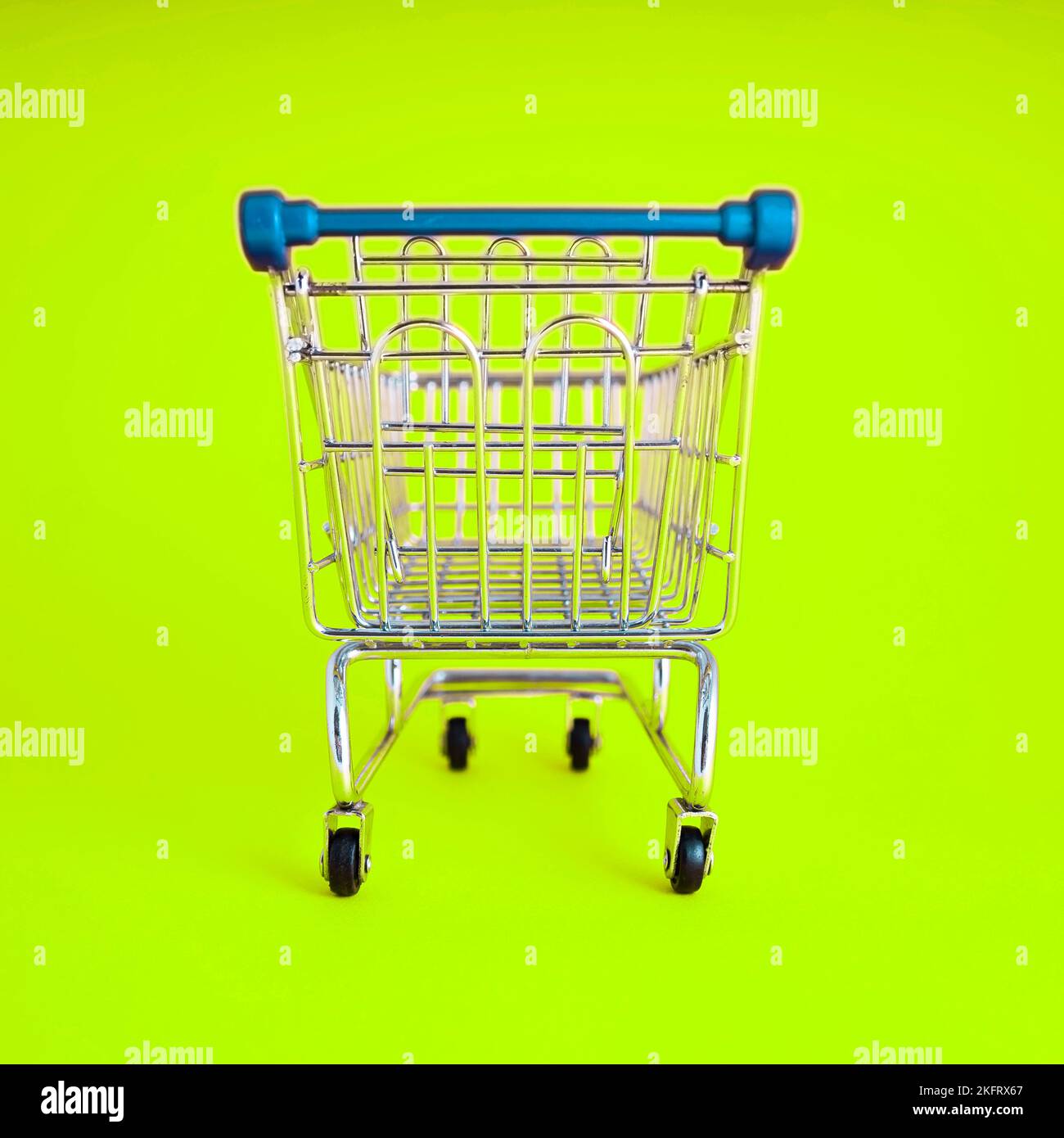 empty shopping cart over colour background, mini metal cart isolated on color background Stock Photo