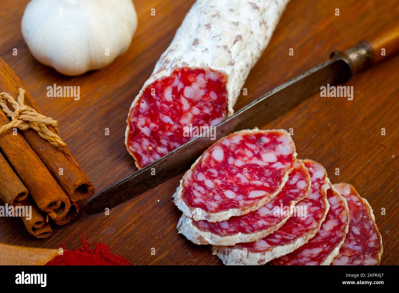 Traditional Italian salame cured sausage sliced on a wood board Stock