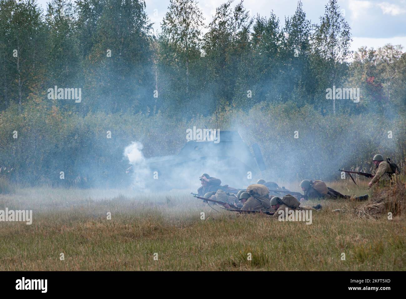 Battle of Soviet and German soldiers. Attack of Soviet soldiers and a smoking armored car. Reconstruction of the battle of World War II. Russia, Chely Stock Photo