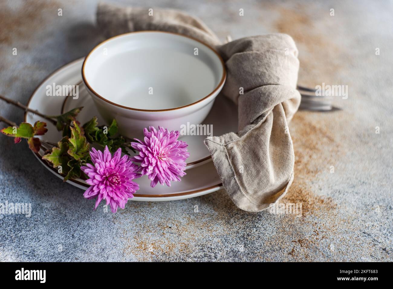 Place setting with purple Chrysanthemum flowers on concrete table with plates Stock Photo