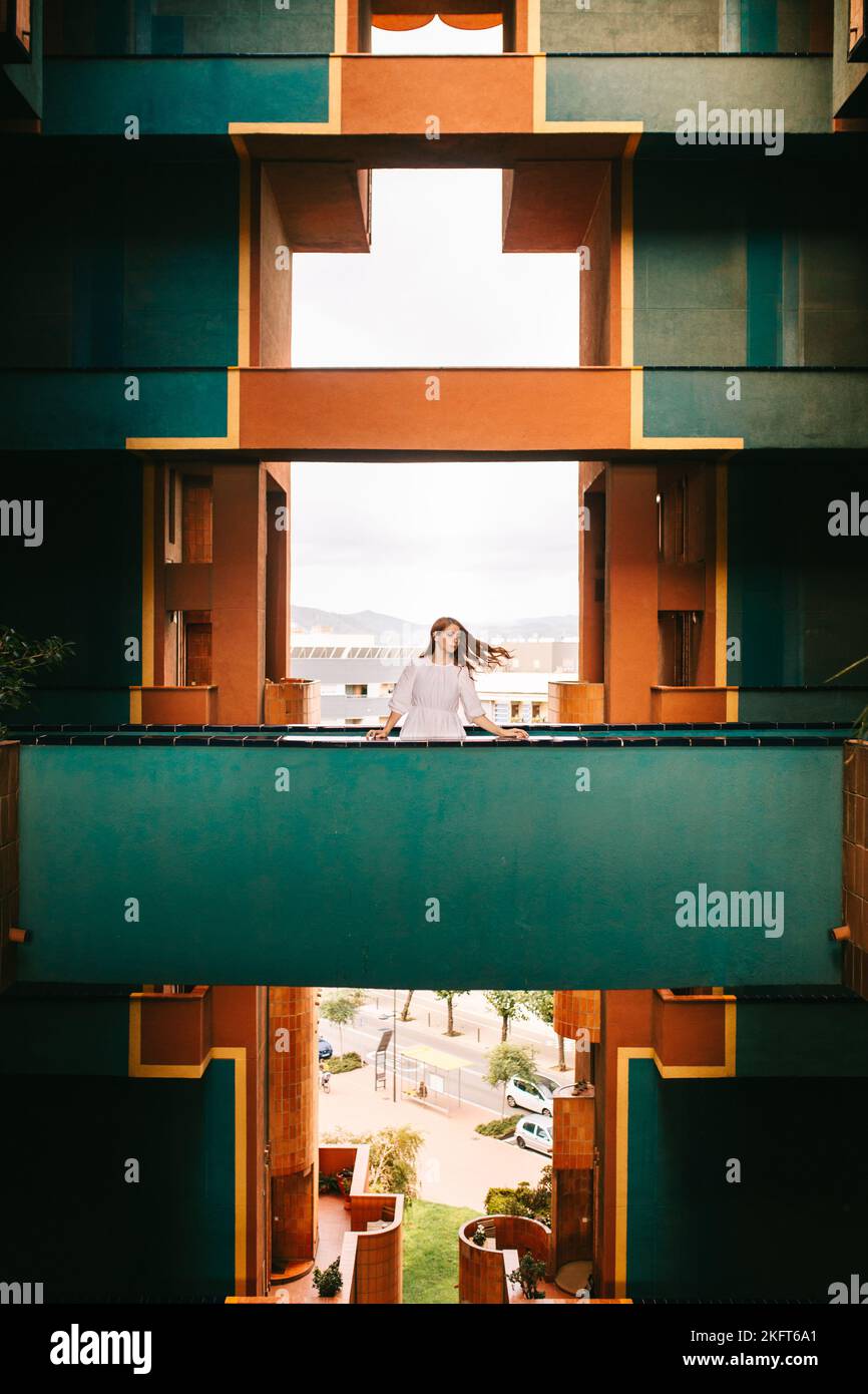 Female model walking on balcony with green walls against geometric huge window in old landmark building in Barcelona Stock Photo