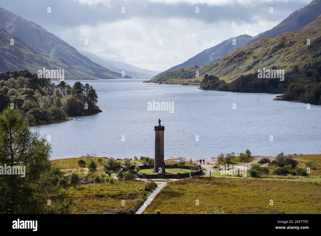 Scenic view of old Glenfinnan Monument located on shore of lake in Scotland surrounded by hills and green trees Stock Photo