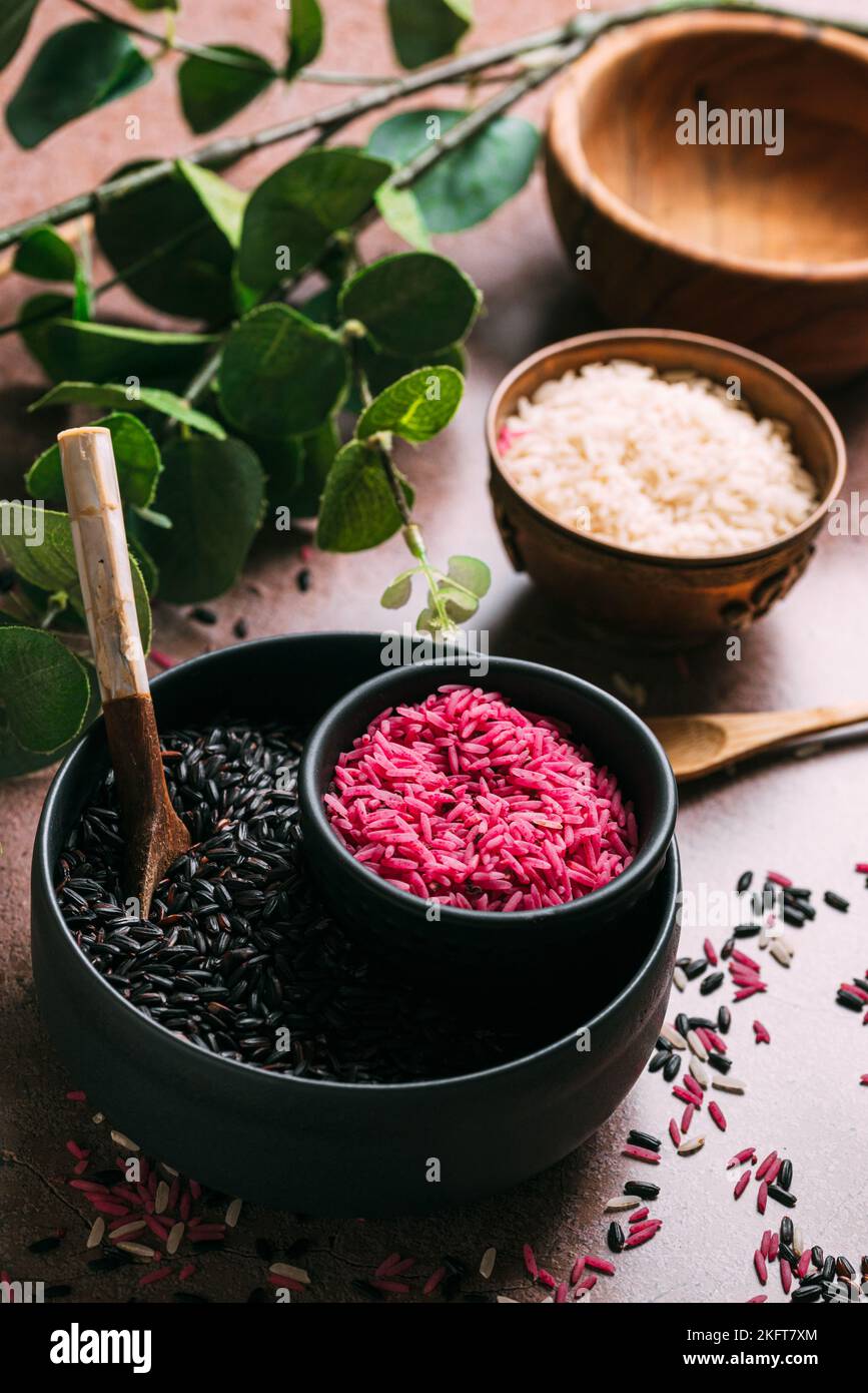 From above bowls with different types of rice placed on table near fresh eucalyptus sprigs Stock Photo
