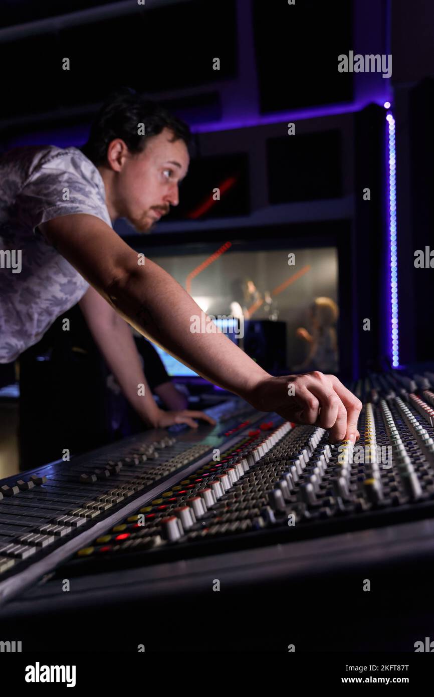 Crop male sound engineer using mixer console editing sounds in studio