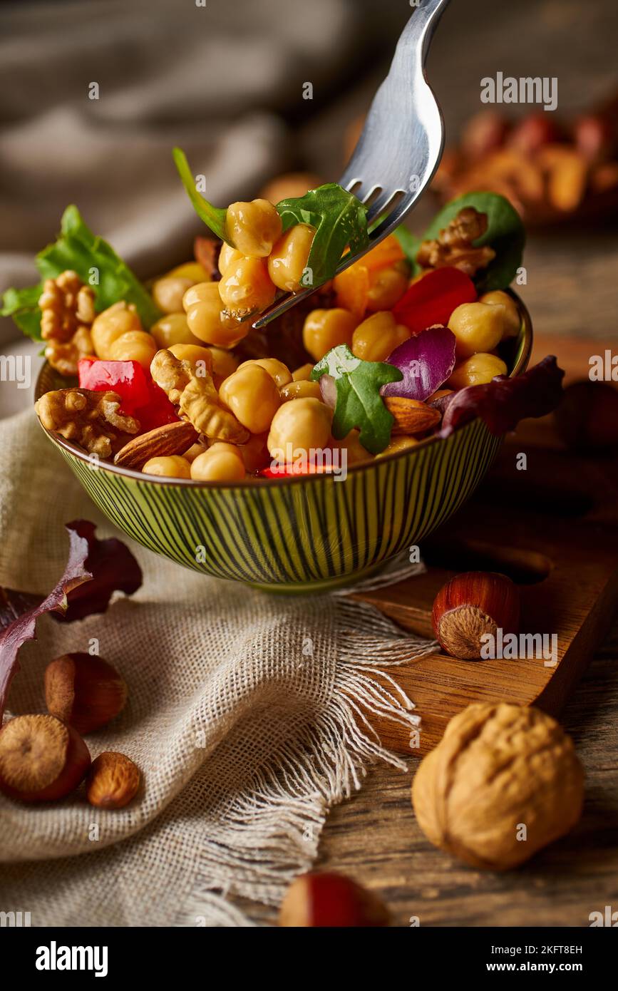 From above appetizing colorful cut vegetable mix with chickpeas and walnuts on wooden background Stock Photo