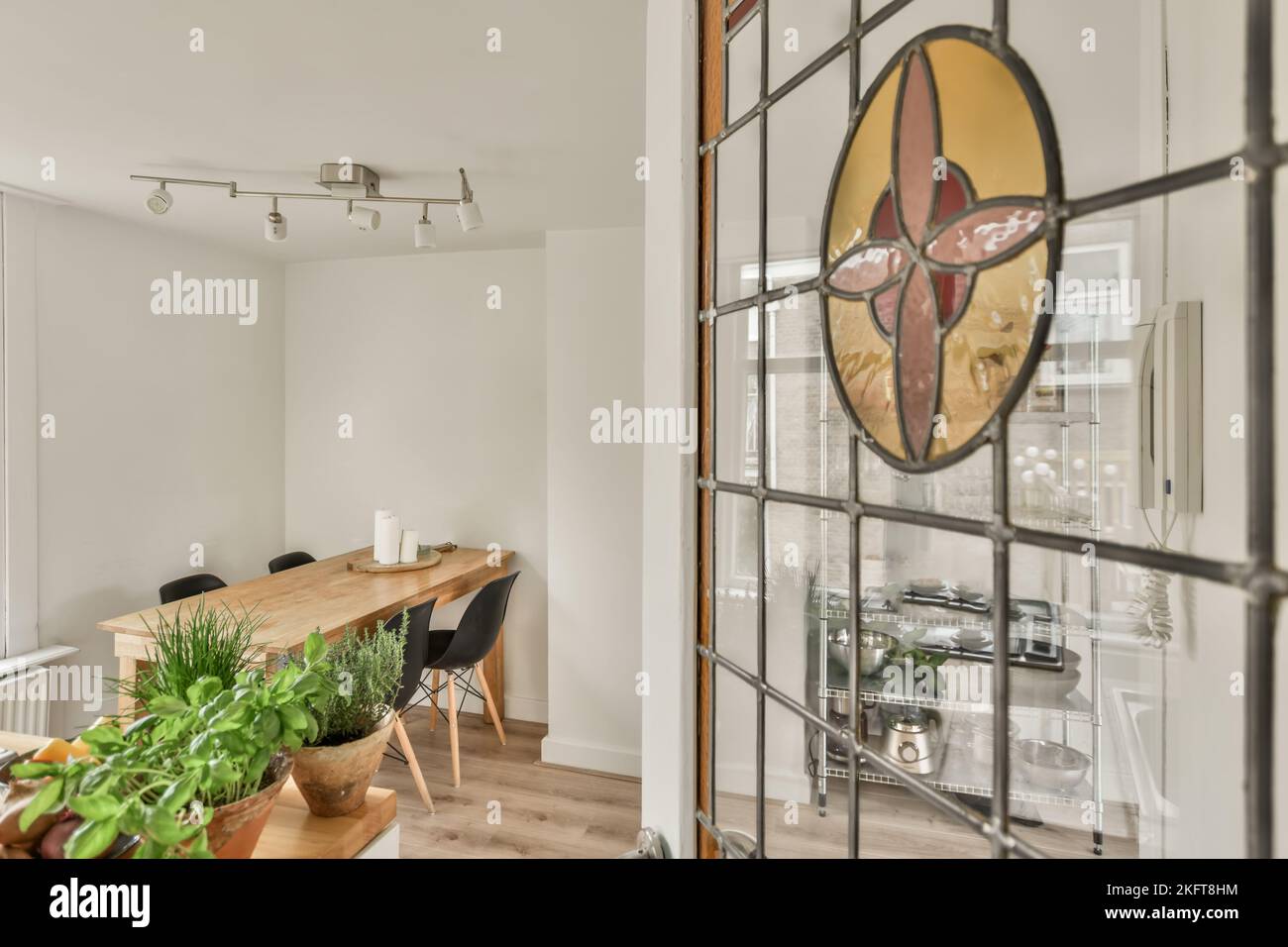 Interior of bright modern home with table and chairs under lamp next to glass door Stock Photo