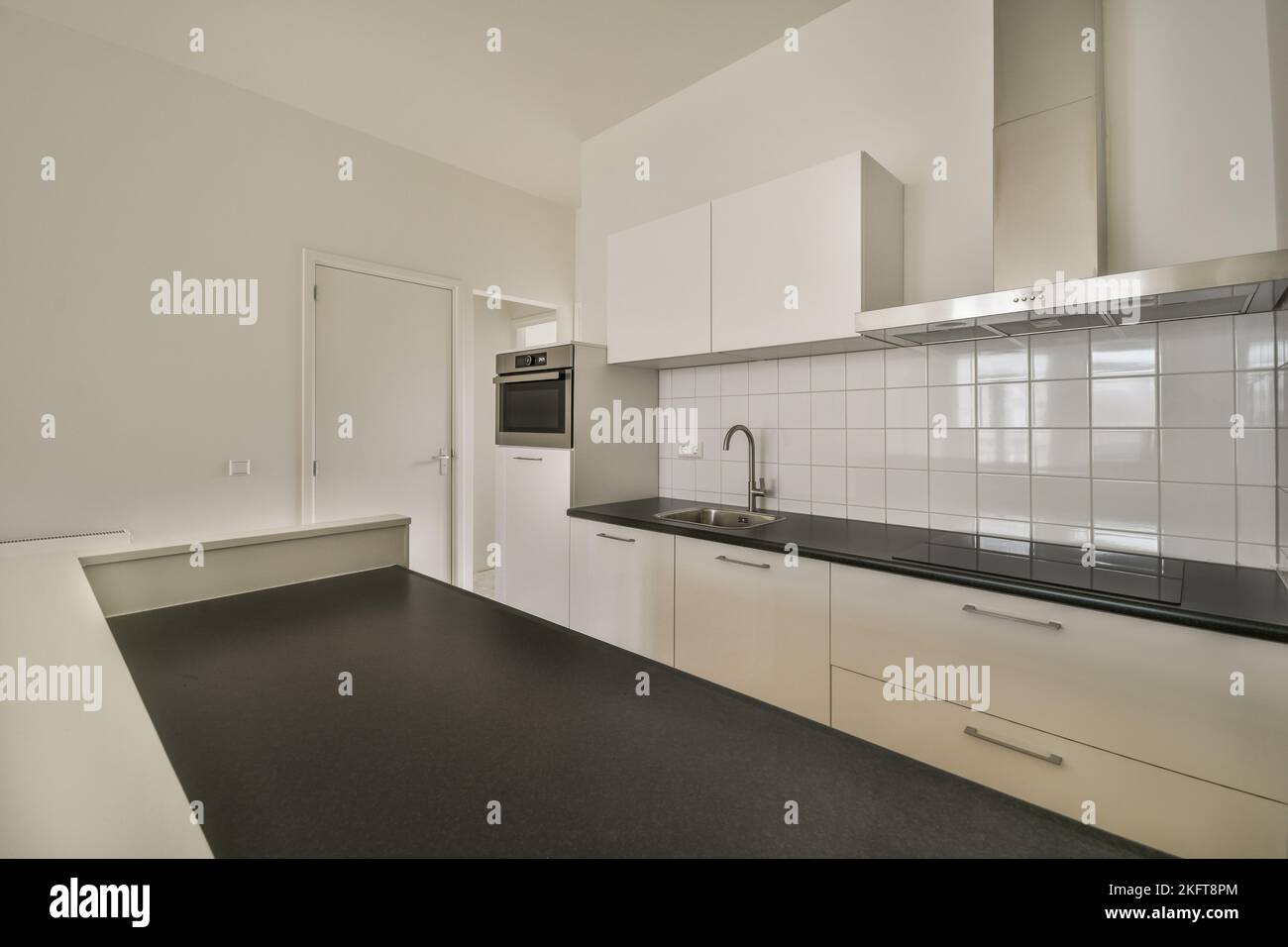 White counters with sink and appliances located against wall with built in furniture in light kitchen at home Stock Photo