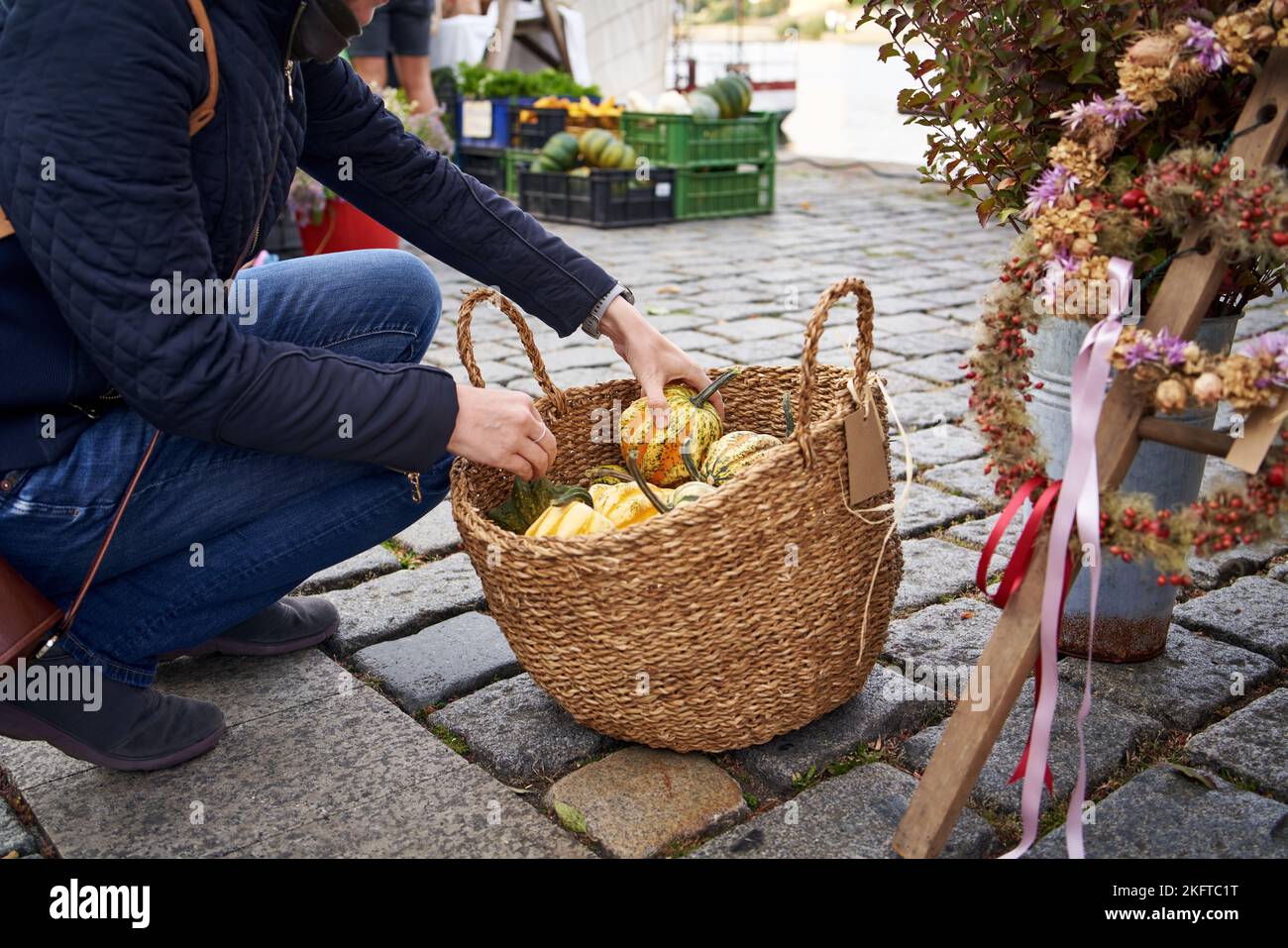 Woman selecting gourds or pumpkins in a basket at the farmers market in autumn Stock Photo