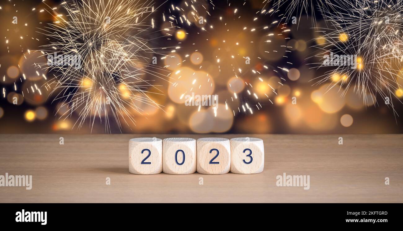 2023 - Wooden cubes with year number. New Year Celebration with fireworks and abstract blurred lights background. Stock Photo