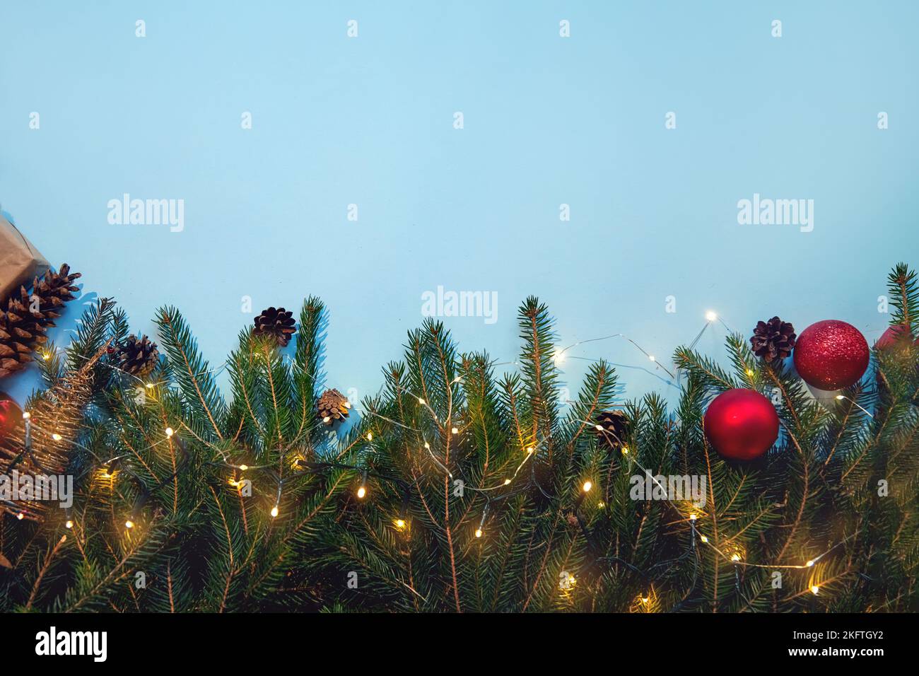 Beautiful Christmas composition on blue background. Christmas present boxes,socks, fir spruce branches,, conifer cones, caramel stick, gift. New Year. Stock Photo