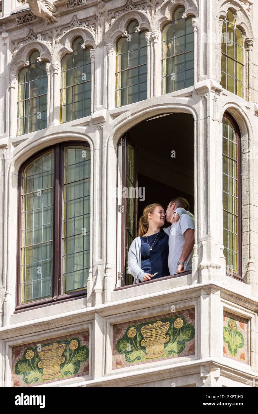 Couple kissing at the window of an old building in Brussels, called La Pharmacie anglaise. Stock Photo