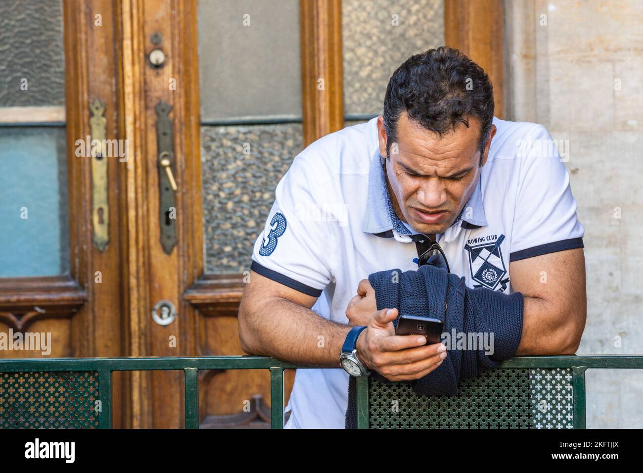 Hefty man consulting his smartphone with a worried expression. Brussels. Stock Photo