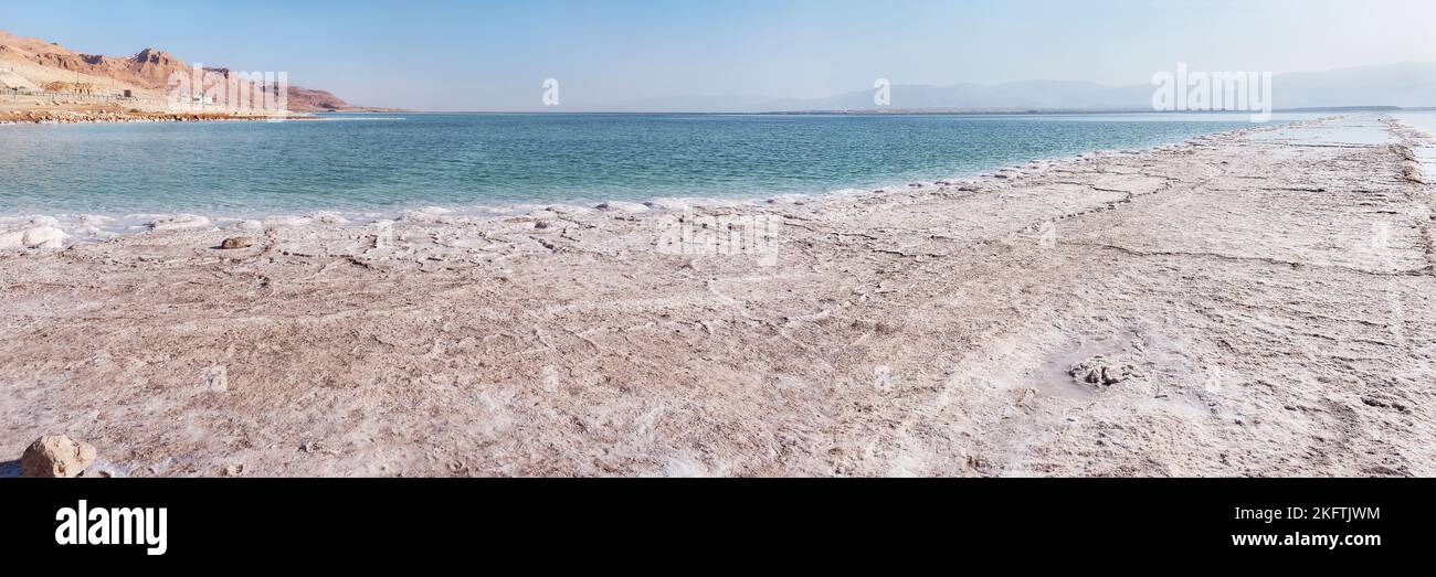 wide surreal panorama that shows large flat industrial salt formations with the Dead Sea and barren desert hills in the background Stock Photo