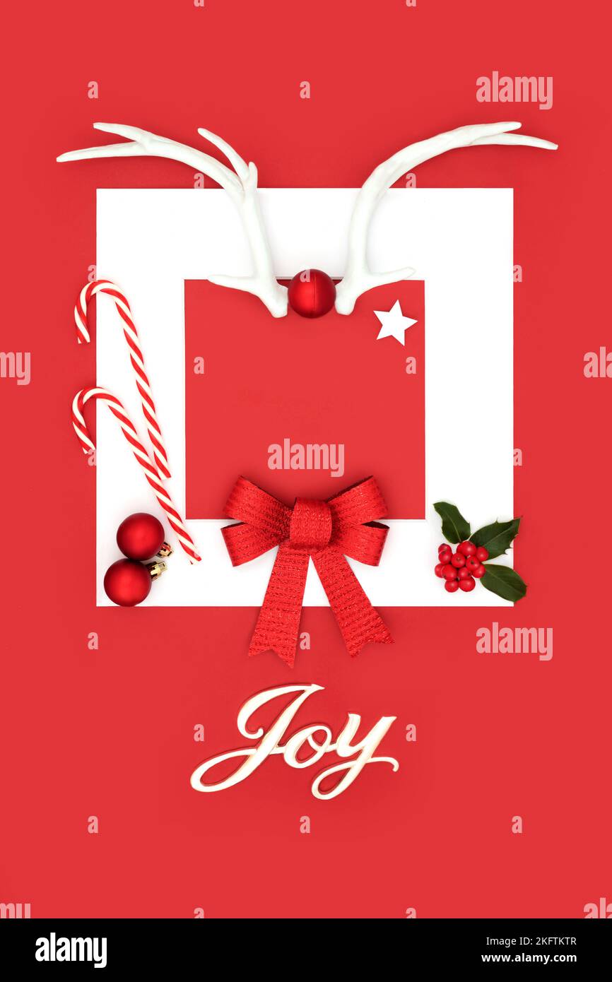 Christmas joy sign festive background with reindeer antlers, bow, holly, baubles on red with