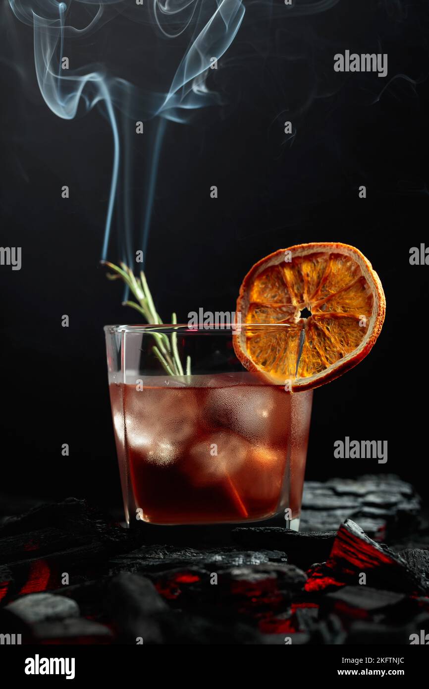 Oldfashioned cocktail with ice, dried orange slice, and rosemary