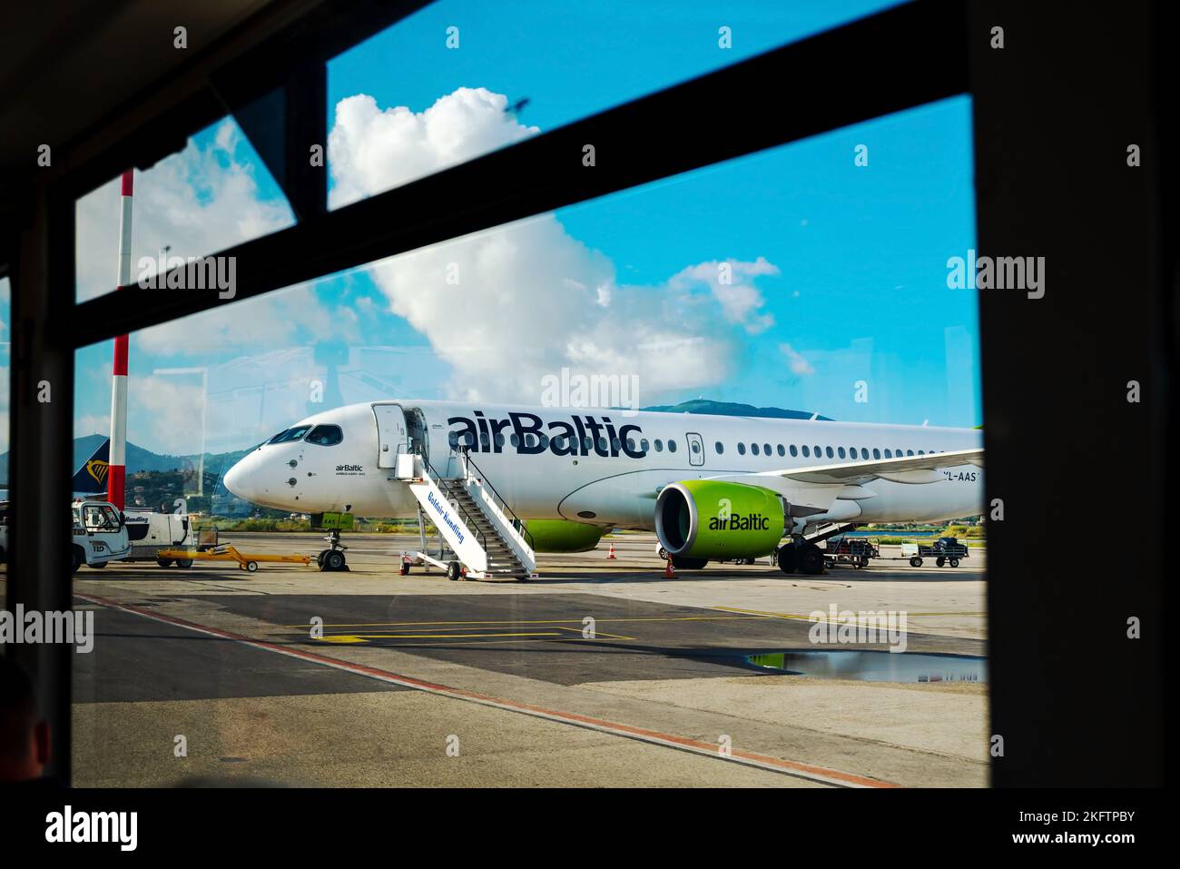 Kerkyra, Greece - 09 29 2022: View From Window of Corfu Airport On Green Plane of AirBaltic. Parking Lot For Aircraft, Aircraft Is Loaded With Luggage Stock Photo