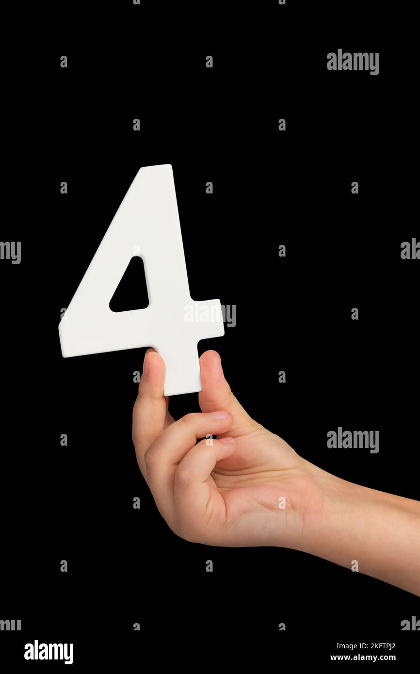 Number four in hand isolated on black background. Number four in a child's hand, holding on a black background. To be inserted into a project or Stock Photo