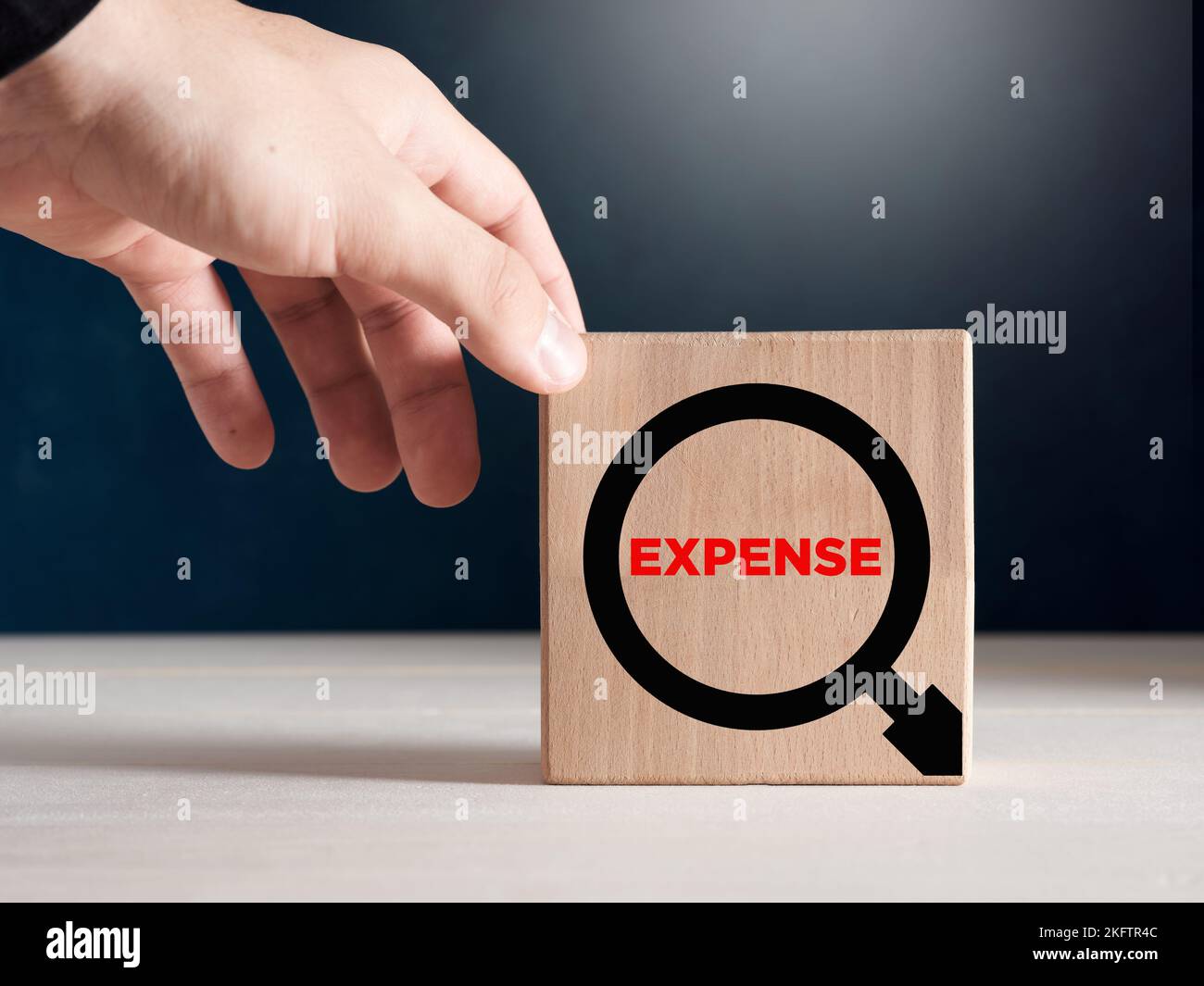 Male hand places the wooden cubes with the word expense with a magnifying glass icon. Expense analysis concept. Stock Photo