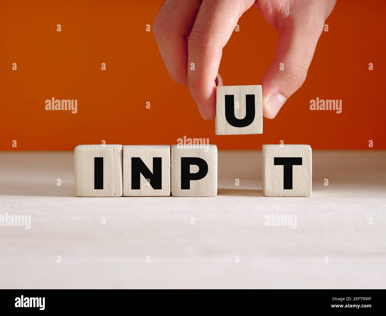 Hand puts the wooden cube with the word input. Business or technology input and factors of production concept. Stock Photo