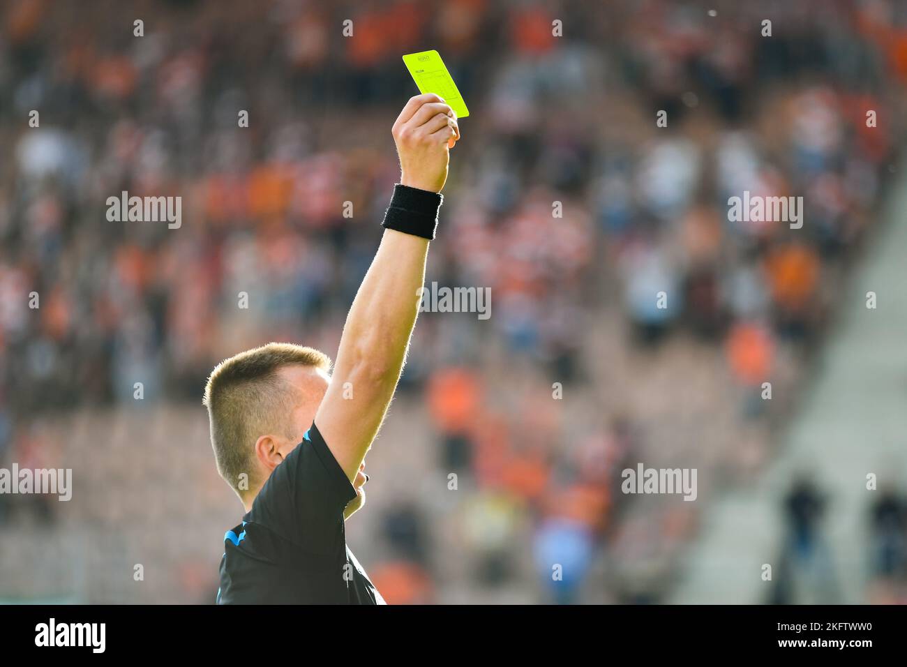 Referee shows yellow card during soccer match at the stadium Stock Photo