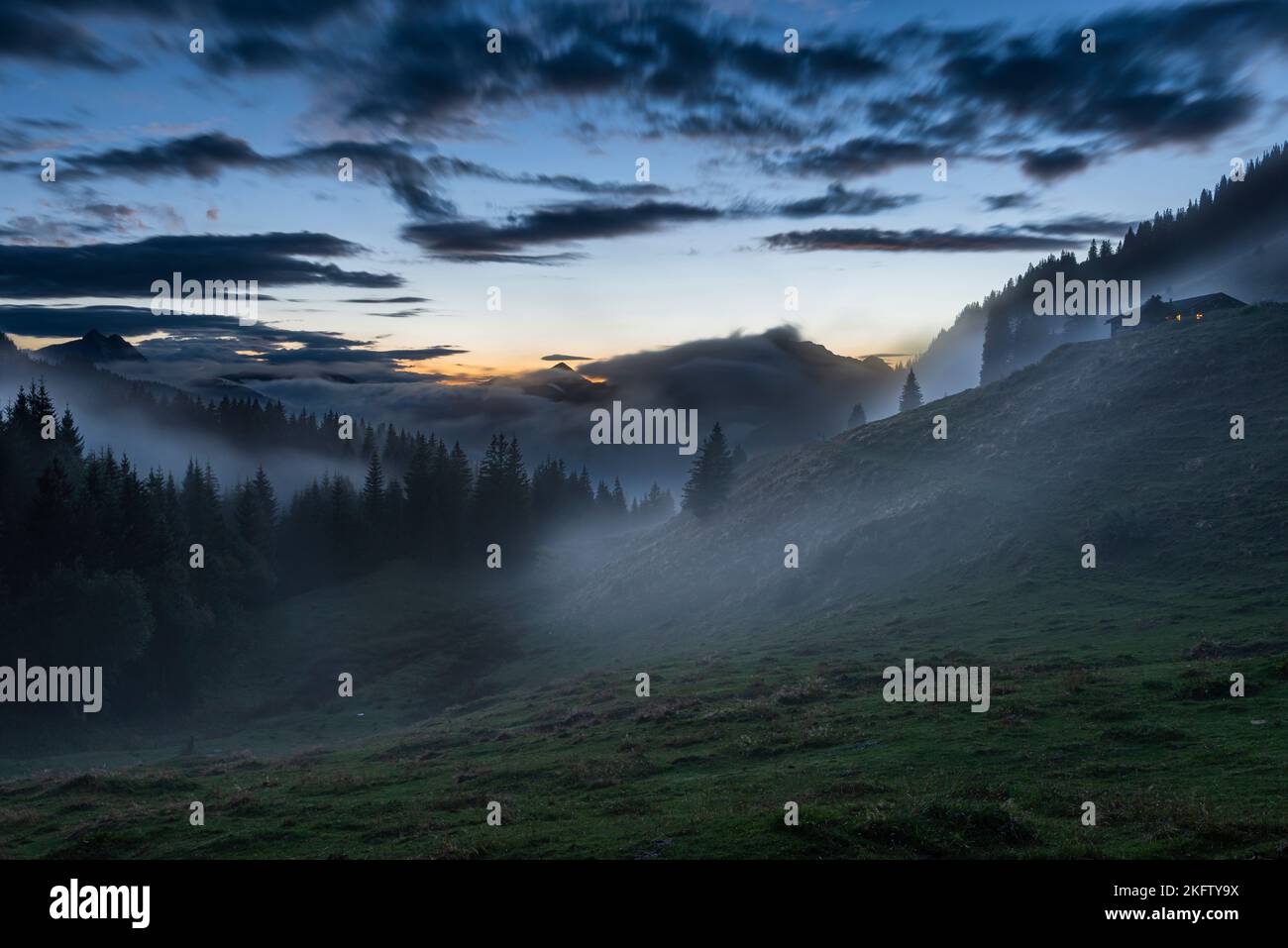 Clouds of fog drift through the mystic mountain forest landscape at the Ackernalm alp after a summer thunderstorm at dusk, Tyrol, Austria Stock Photo