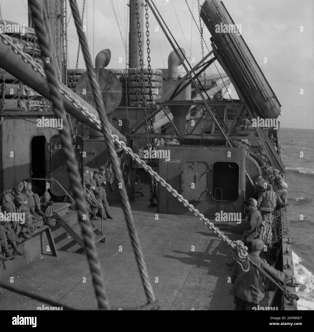 Men sitting on deck of ship. United States Army veterans coming home on the Elgin Victory ship at the conclusion of World War II. SS Elgin Victory, a type VC2-S-AP2 Victory ship built by Permanente Metals Stock Photo