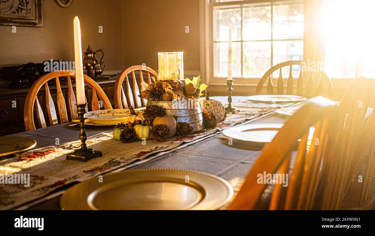 An empty Thanksgiving Dinner table with wooden chairs with sunset light